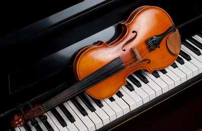 Violin resting on a piano keyboard